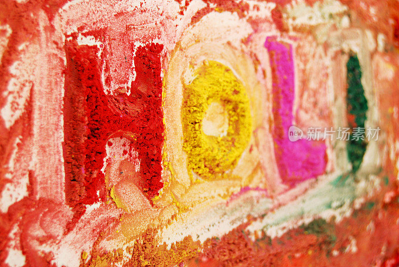 这是一种由胡荽粉混合而成的鲜艳的红色、绿色、黄色和品红粉的混合物，在白色的背景上洒上或洒上文字H O L I，用胡荽粉形成的rangoli图案